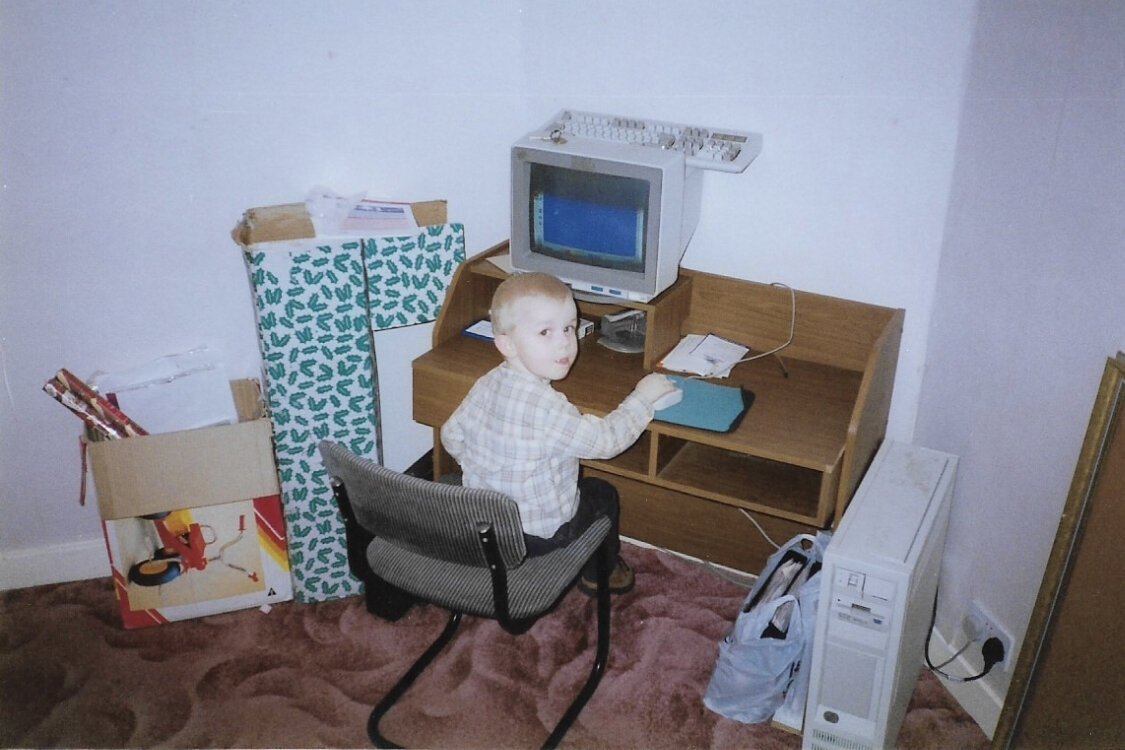 Daniel as a small child sitting at an early home computer desk