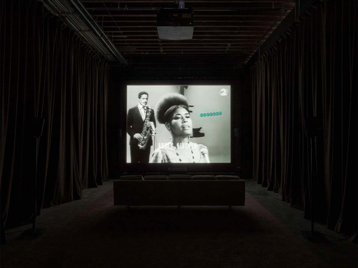 Installation view of Black Poirot at Pioneer Works, Brooklyn: archive footage projected in a dark, curtained room