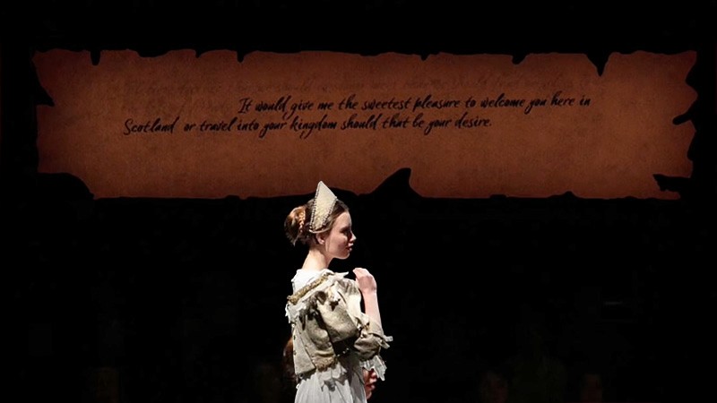 Queen Elizabeth I (Claire Wetherall) reads a letter as handwritten parchment captions glow above; simulation still.