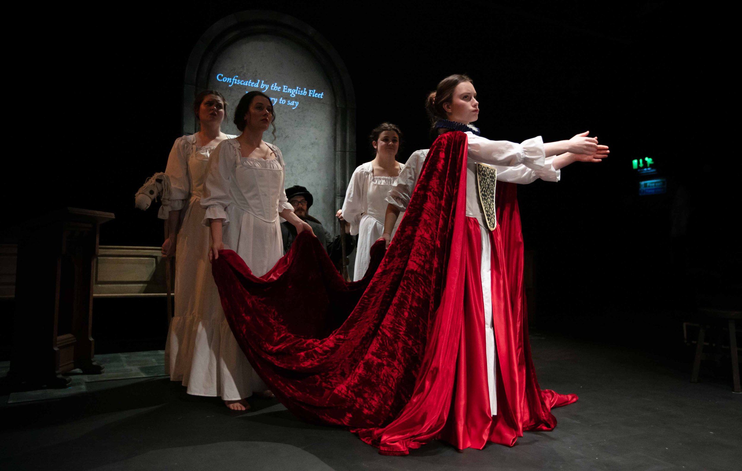 Claire Wetherall as Mary in a sweeping red cloak with Amy Murray, Irina Vartopeanu, Neil Shand and Emery Hunter behind her.