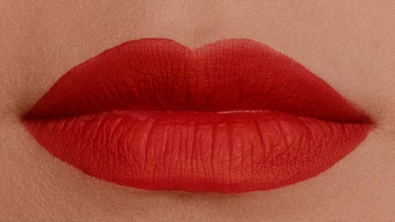 Extreme close-up of a mouth wearing matte red lipstick
