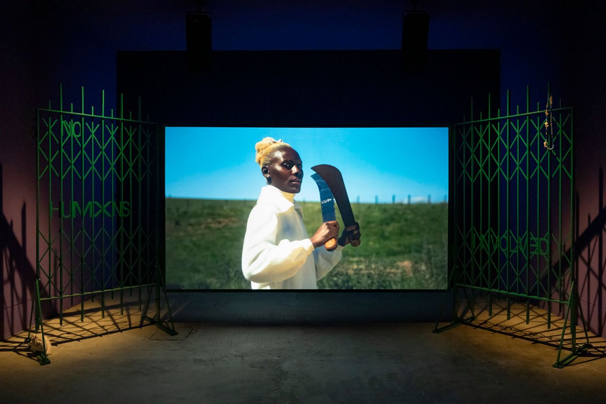 Installation view of Lagareh at Scotland+Venice, Venice Biennale: green gates flank a glowing film screen