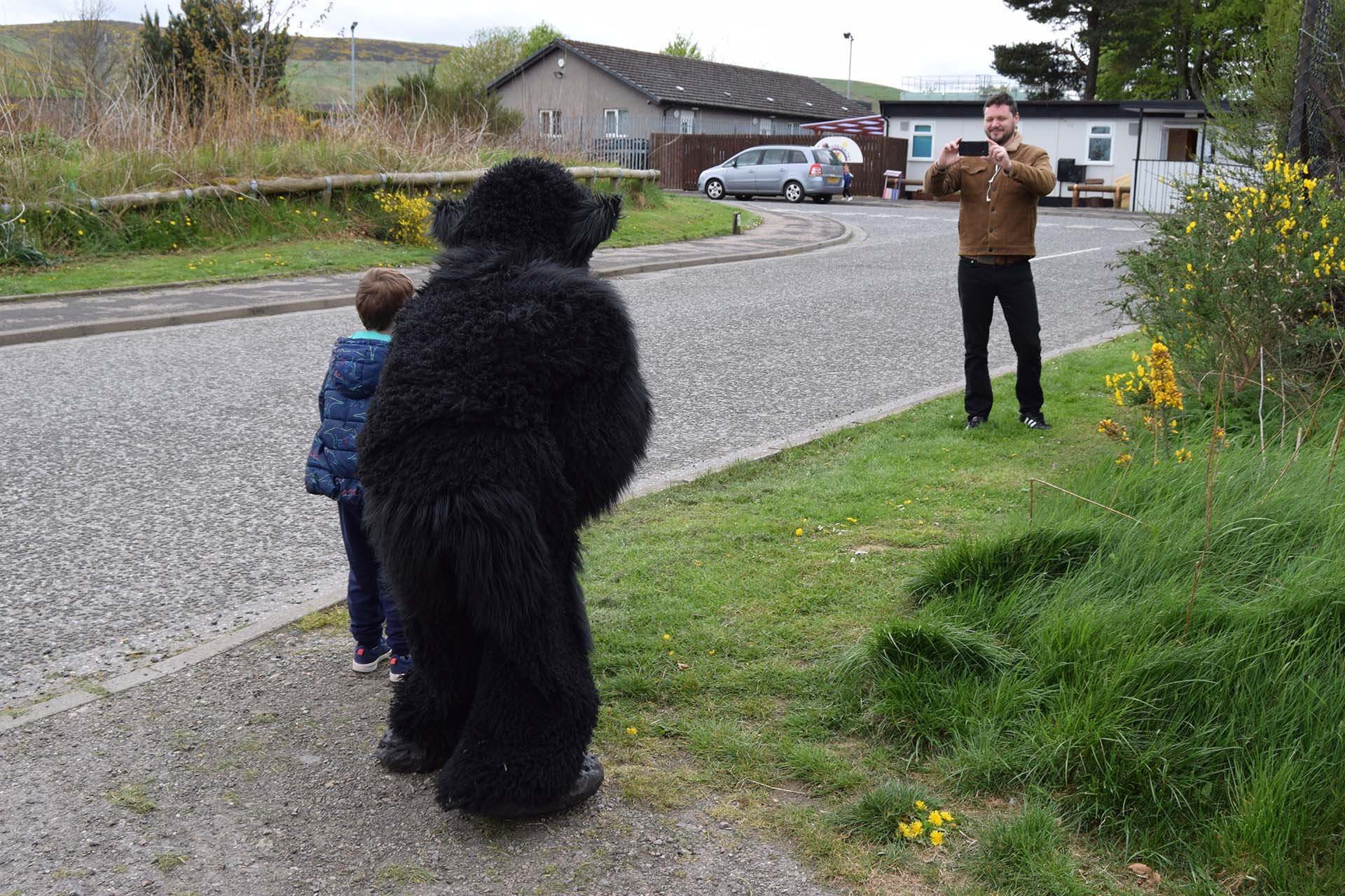 Lilo, in the monster costume, poses by the roadside with a young local fan as a man takes their photo