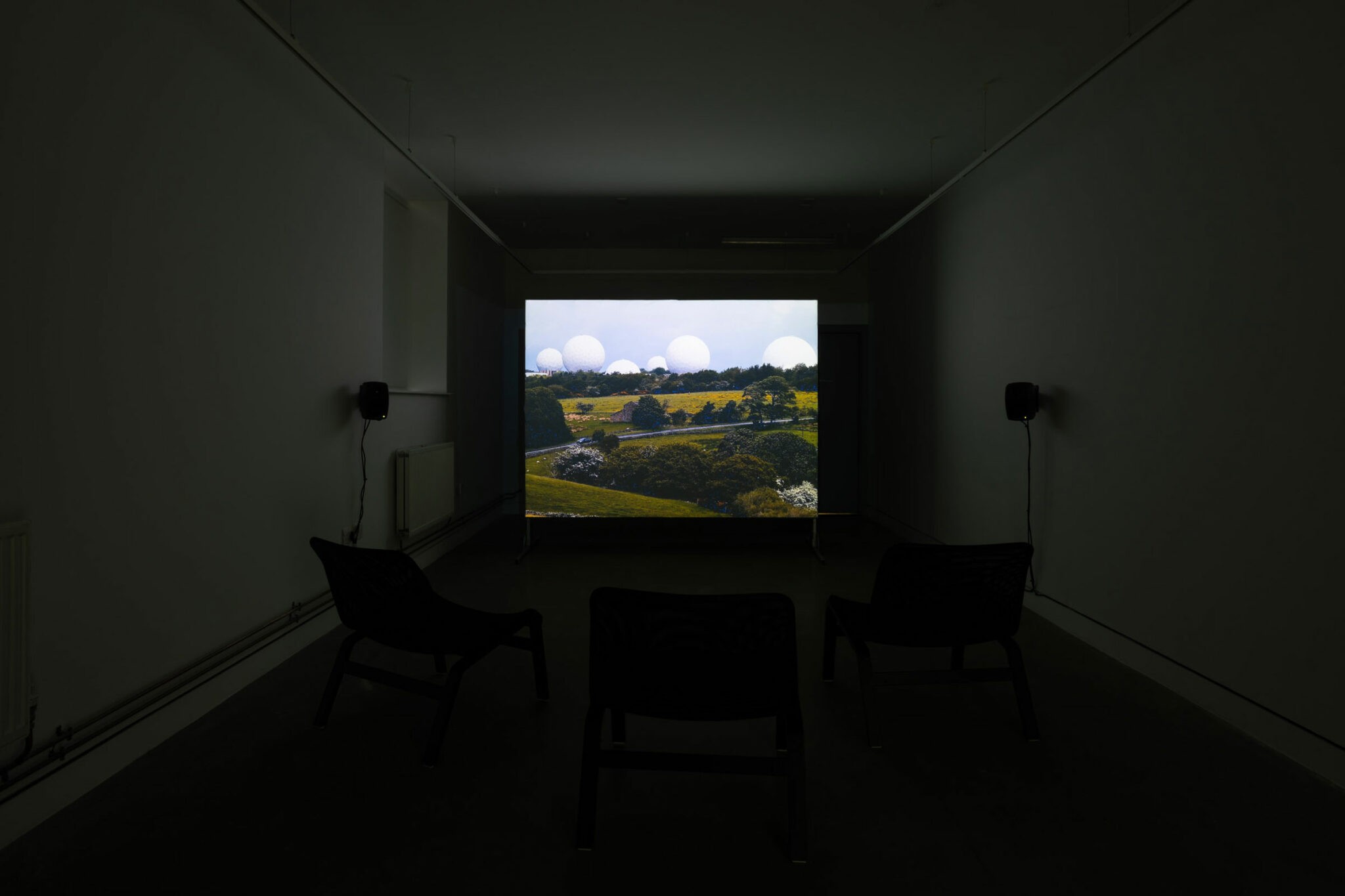 Installation view of On Clogger Lane at Yorkshire Contemporary, Leeds: projected valley landscape with white radomes
