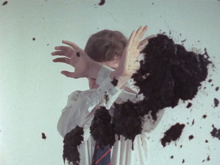 Film still from Penda's Fen dir. Alan Clarke: a boy shields his face as mud splatters across his white shirt