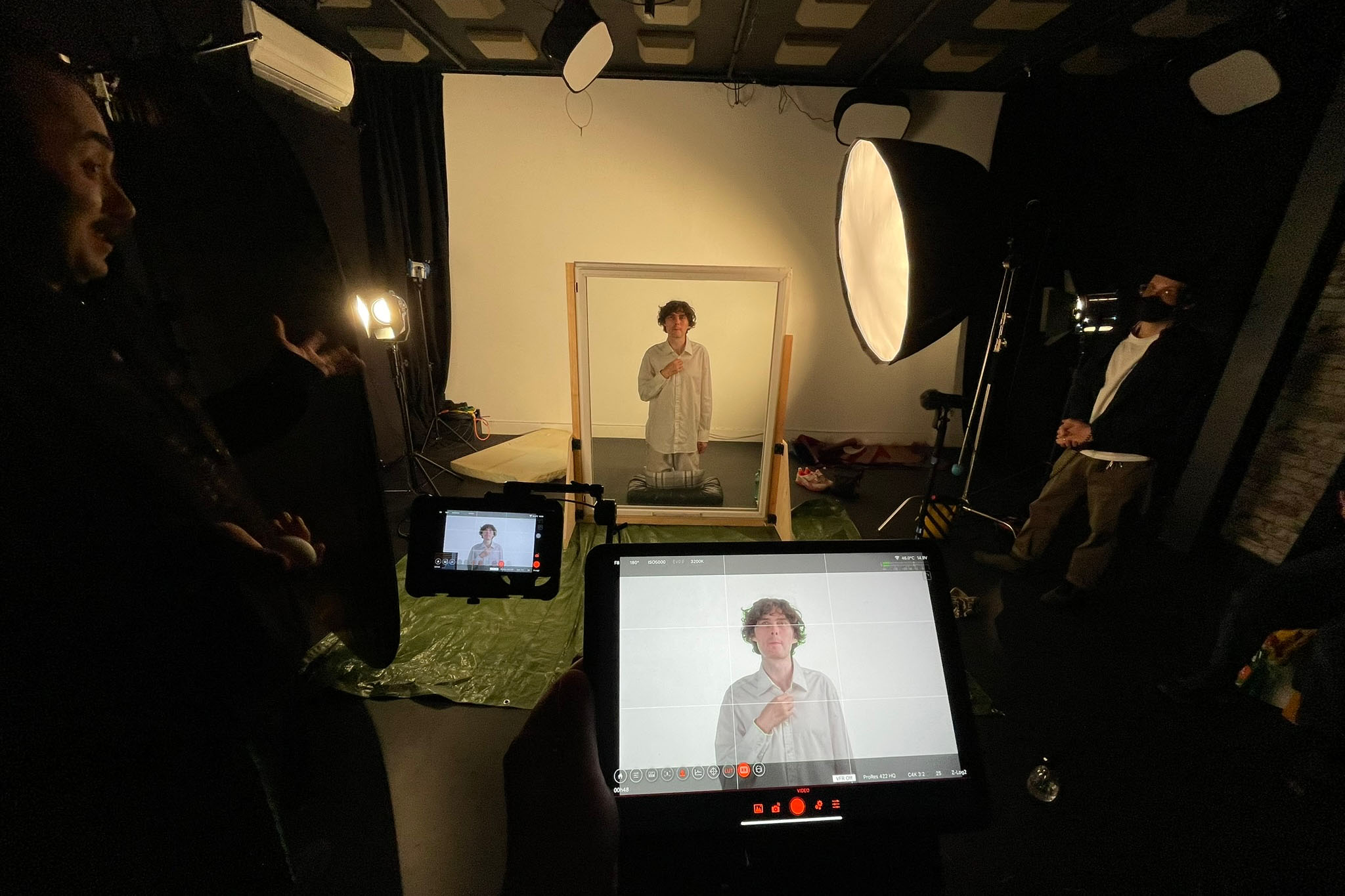 Behind the scenes at Up Next Studios, Glasgow: Alfie stands behind a glass pane between lights and camera monitors