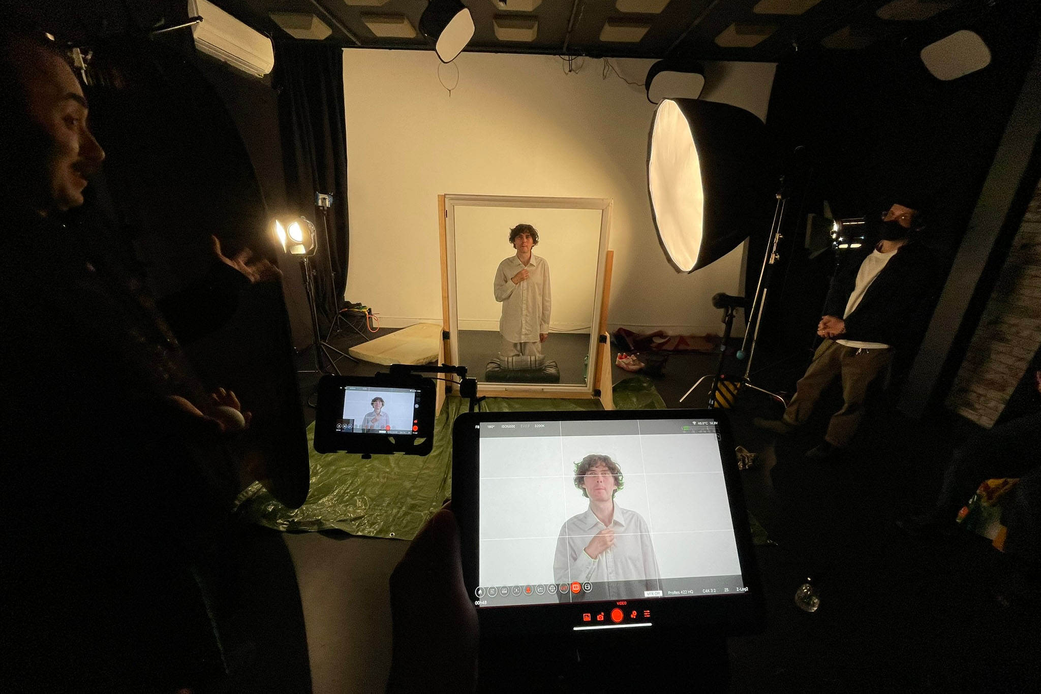 Behind the scenes at Up Next Studios, Glasgow: crew watch monitors as Alfie poses behind a framed glass pane
