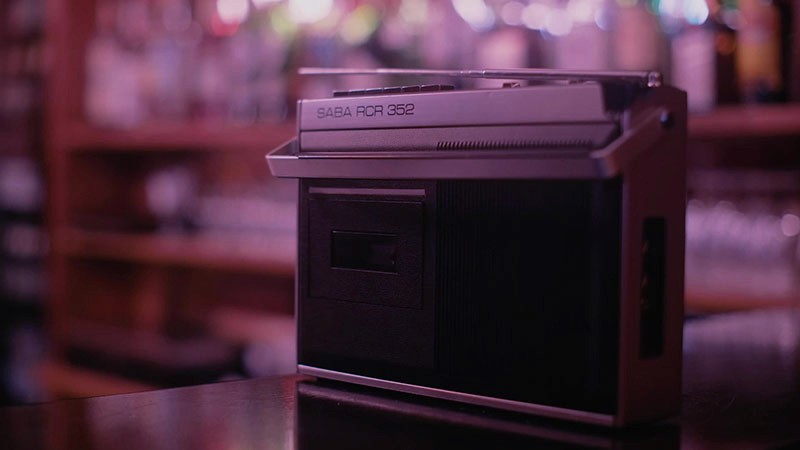 Vintage SABA radio cassette player on the bar, blurred bottles glowing behind