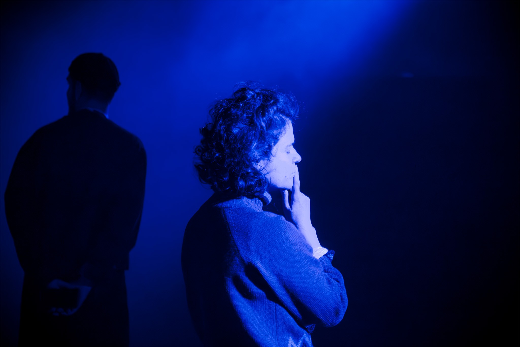 Silhouettes of Alexandar Hadjiev and Ksenia Ravvina deep in thought, bathed in blue light